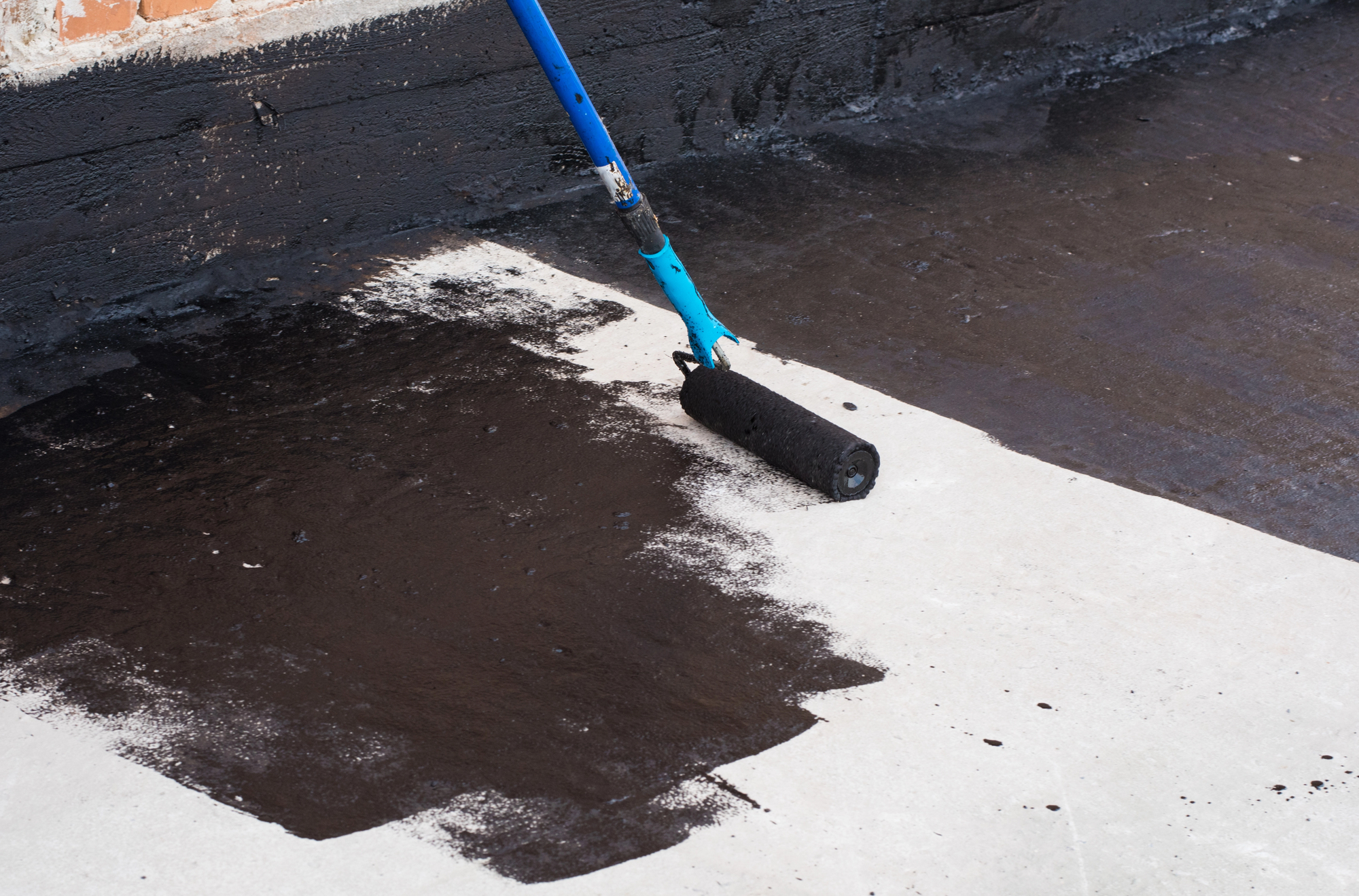 worker putting concrete sealing on concrete driveway