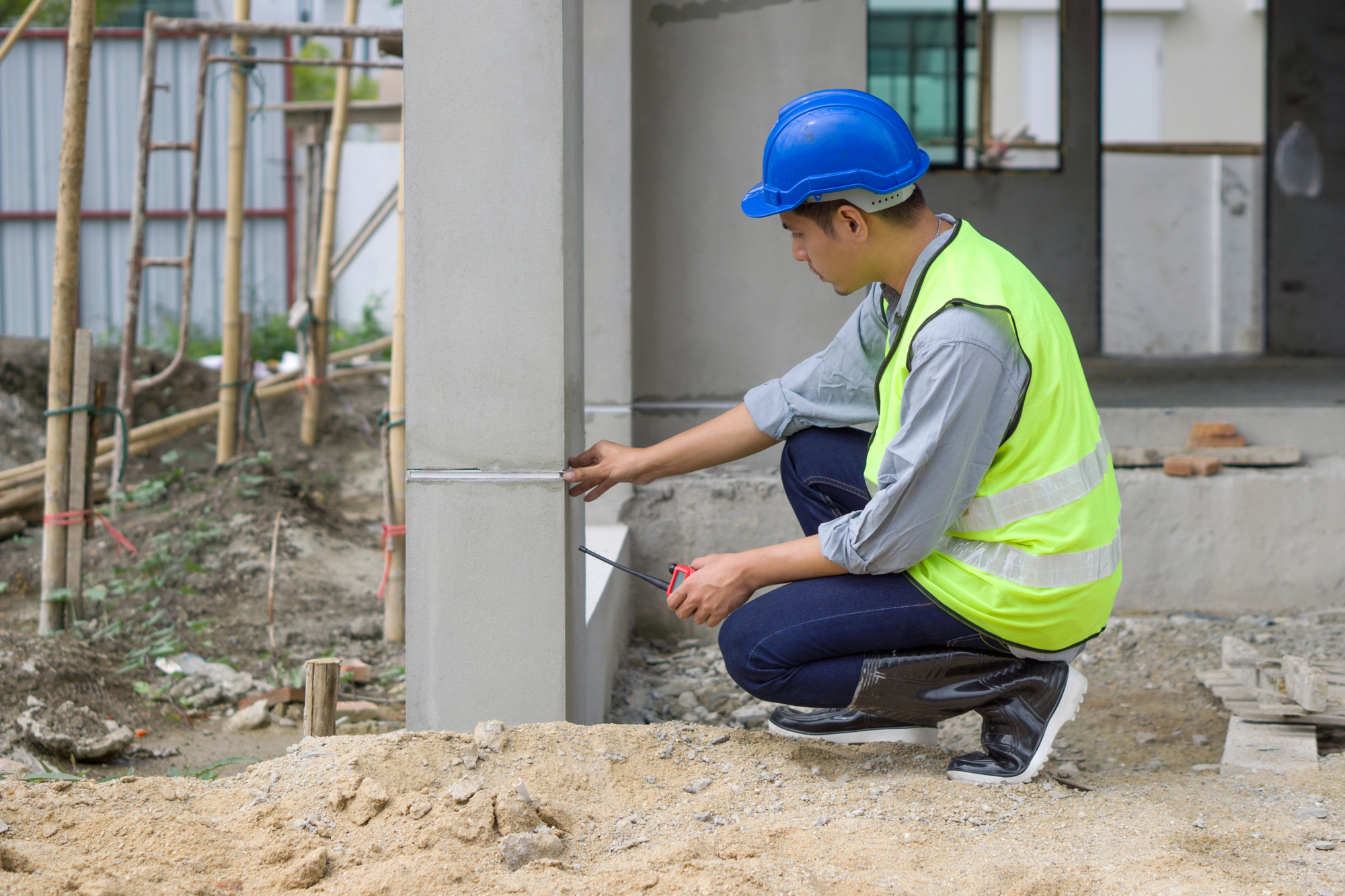 Young engineer in a construction helmet and safety vest checking house structure
