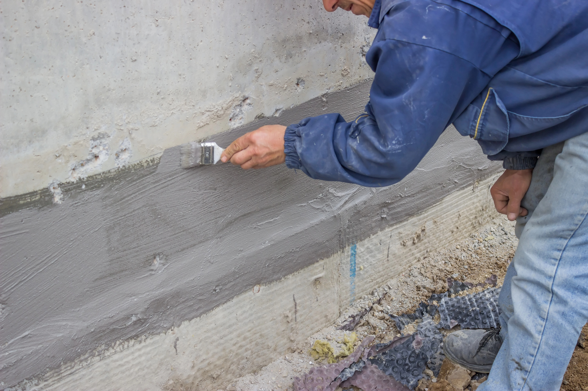 Construction worker with brush applied hydro insulation